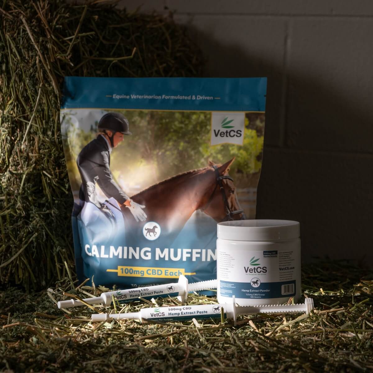 VetCS horse calming muffins, hemp extract powder, and hemp extract paste on a bail of hay