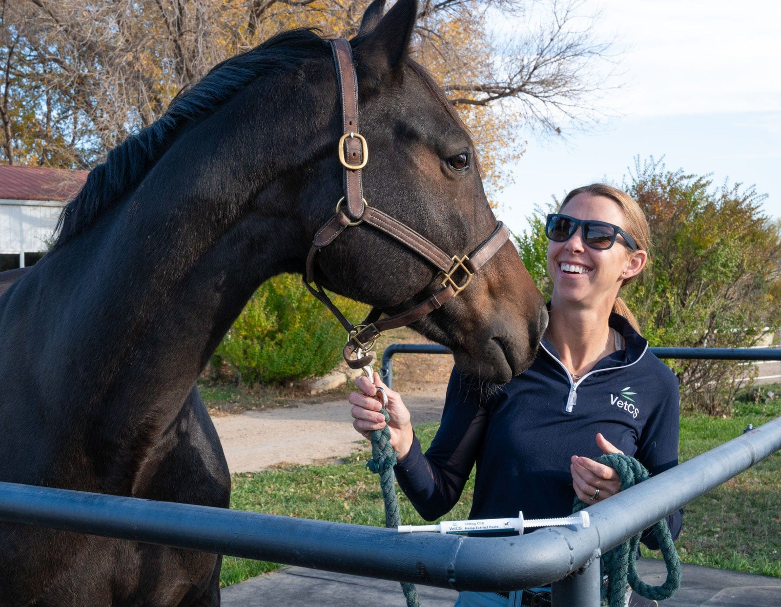 Dr. Luedke laughing with a horse outside with a syringe of medication for horses.   
