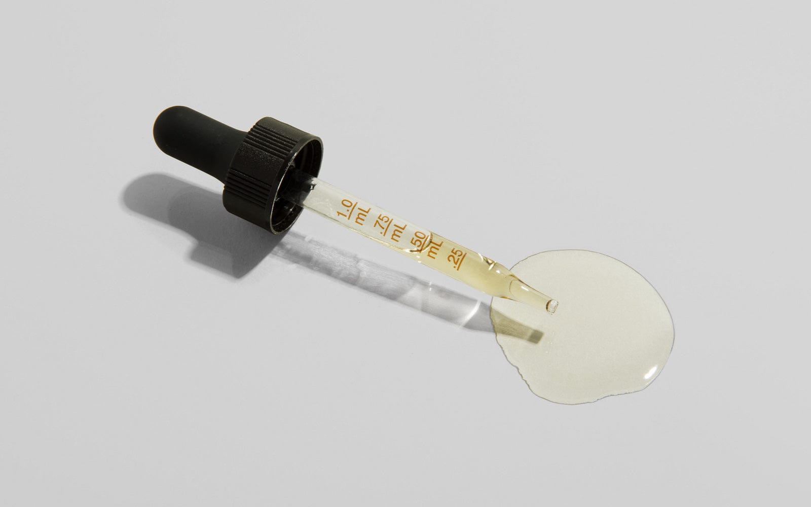 CBD oil dropper with liquid spilled on a clean surface, representing natural support options for dogs with seizures.