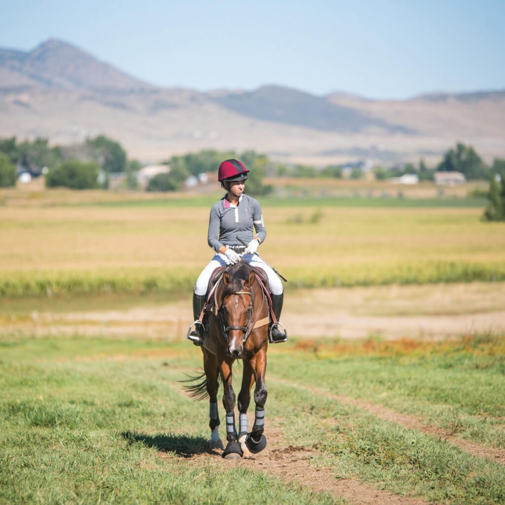 image of women ridding a horse in a Colorado field 
