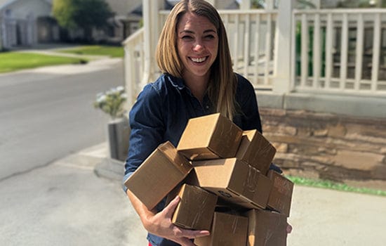 VetCS co-founder Chelsea smiling while carrying a stack of customer orders, showing the hands-on dedication behind the brand’s early growth.