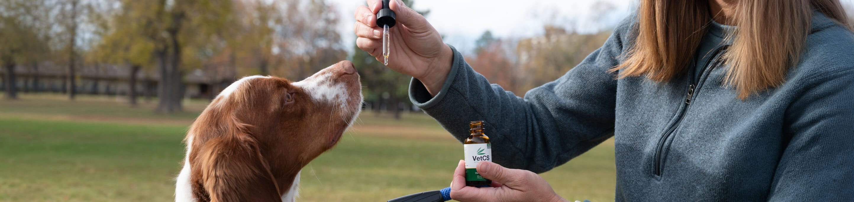 Dr. Chelsea Luedke holding a bottle of CBD oil for a dog outdoors.